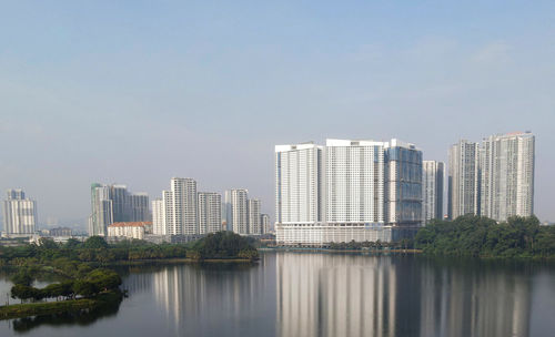 Modern buildings by river against sky in city