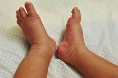 Low section of baby feet on bed