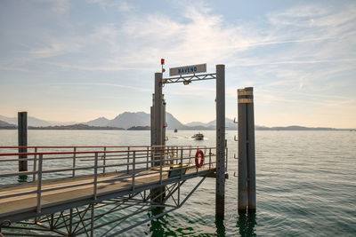 Landing stage of baveno city with boat and mountainous coast in the background at sunrise