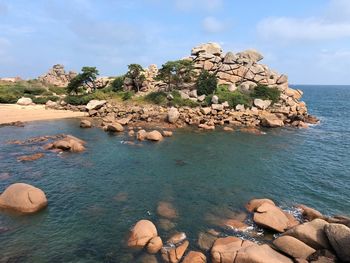 Rocks on shore by sea against sky