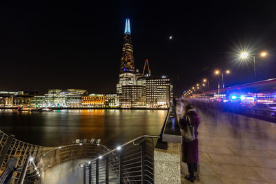 River against illuminated buildings in city at night