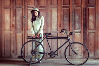 Portrait of smiling young woman leaning on bicycle