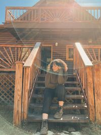 Full length of woman sitting on staircase against house