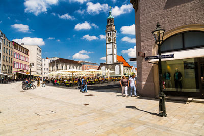 People walking on street in city against sky