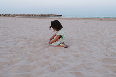 Little girl playing in the sand on the beach at blue hour