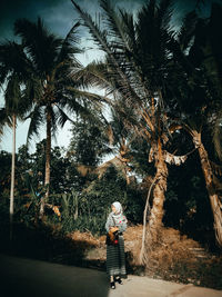 Man and woman standing on palm tree