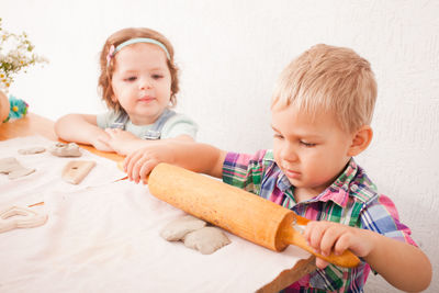 Boy with rolling pin playing with clay at home