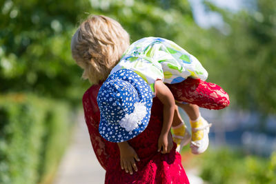 Mother carrying daughter at park on sunny day