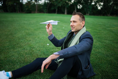 Low angle view of businessman using mobile phone while sitting on field