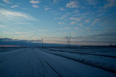 Snow covered landscape against sky during sunset