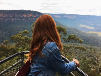 Young woman standing at observation point against landscape