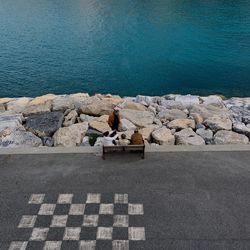 High angle view of woman sitting on rock by sea