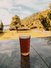 Close-up of beer glass on table against sky