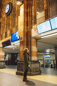 Side view of woman standing by illuminated building