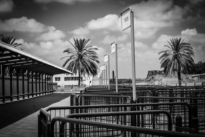 Metallic structure by palm trees against sky