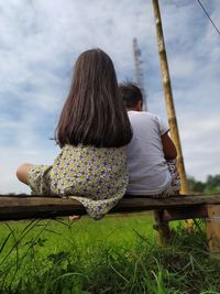 Rear view of women sitting on bench