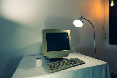 Illuminated electric lamp on table against wall