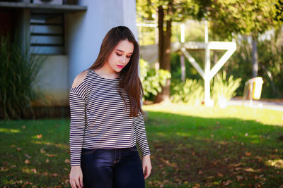 Beautiful woman looking down while standing at park