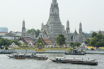 Boats in river against buildings in city