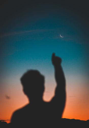 REAR VIEW OF SILHOUETTE MAN STANDING AGAINST ORANGE SKY