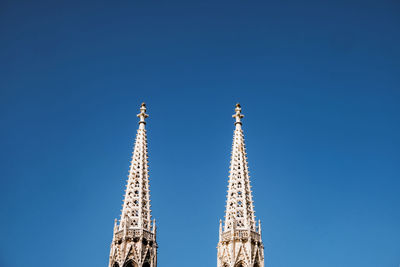 Low angle view of church towers against blue sky in vienna 