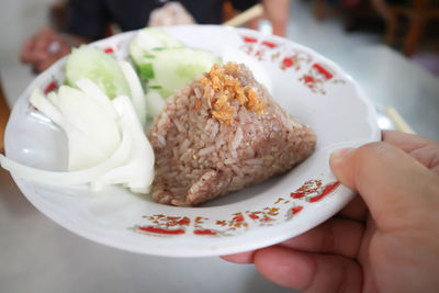 Close-up of hand holding ice cream in plate