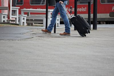 Low section of man walking with luggage in city
