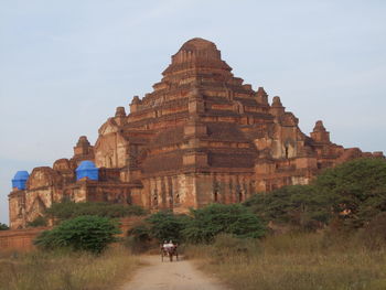 Tourists at temple against sky