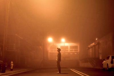 Side view of man walking on street at night