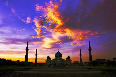 Illuminated building against sky during sunset