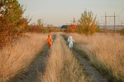 Rear view of men walking on field against sky