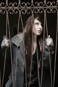 Woman looking away while standing by gate