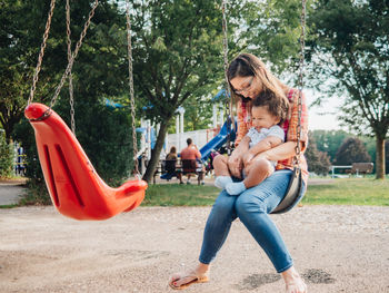 Mother and son sitting on swing at playground