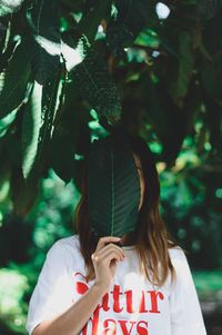 Woman holding leaf over face