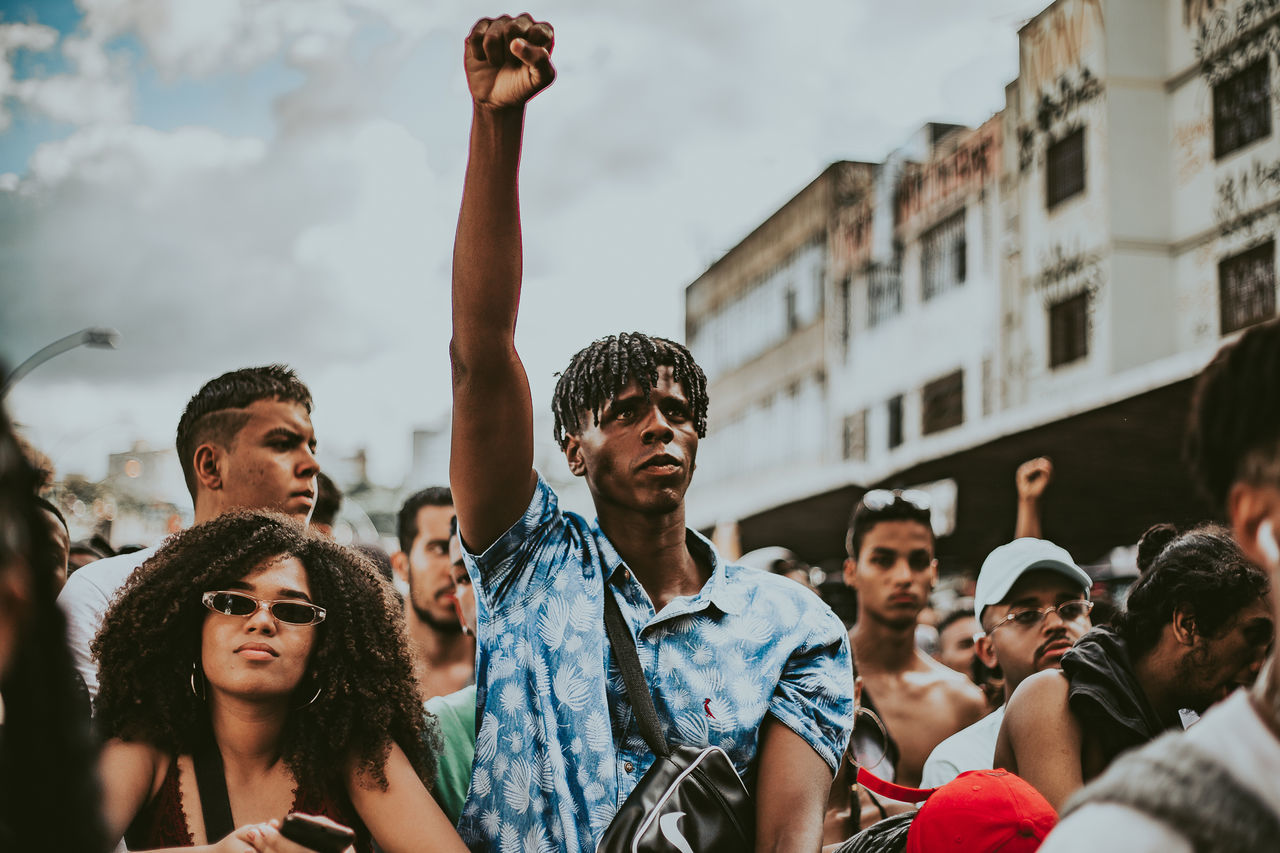 real people, architecture, group of people, crowd, city, leisure activity, lifestyles, men, enjoyment, adult, people, focus on foreground, young adult, looking, young men, built structure, building exterior, day, women, togetherness, outdoors, human arm, watching, arms raised