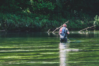 Man holding umbrella against lake in forest