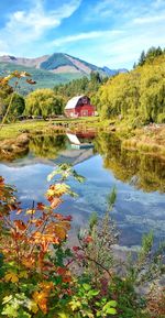 Scenic view of lake by trees and houses against sky