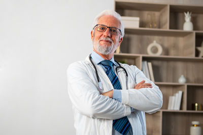 Portrait of doctor standing against wall