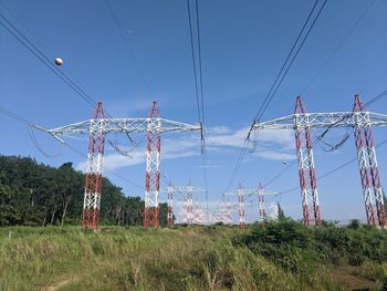Low angle view of electricity pylon on field against clear sky