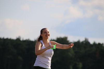 Cheerful woman holding string against sky