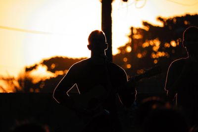 Rear view of silhouette people against sky during sunset