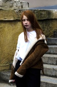 Young woman standing against wall