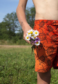 A small bouquet of wildflowers in the hands of a boy. temporary tattoo on a child's hand. 