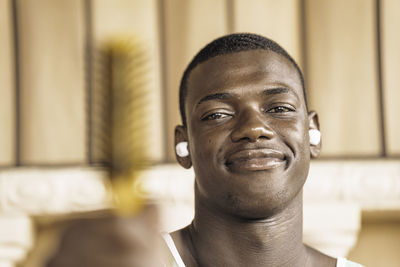Close-up portrait of a young and attractive black man smiling at the camera wearing wireless
