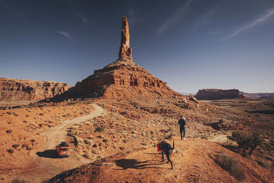 A woman with a child and a dog is standing on a hill at valley of gods