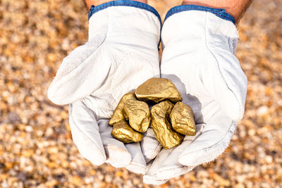 Close-up of hands holding golden stones