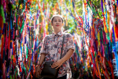 Woman standing amidst colorful prayer ribbons