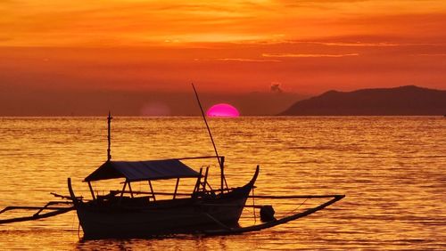 Fishing boat in sea against sky during sunset