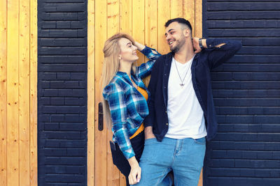 Smiling young couple standing against brick wall