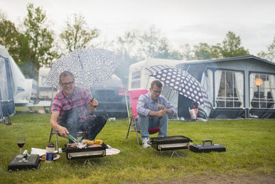 Men barbecuing in rain